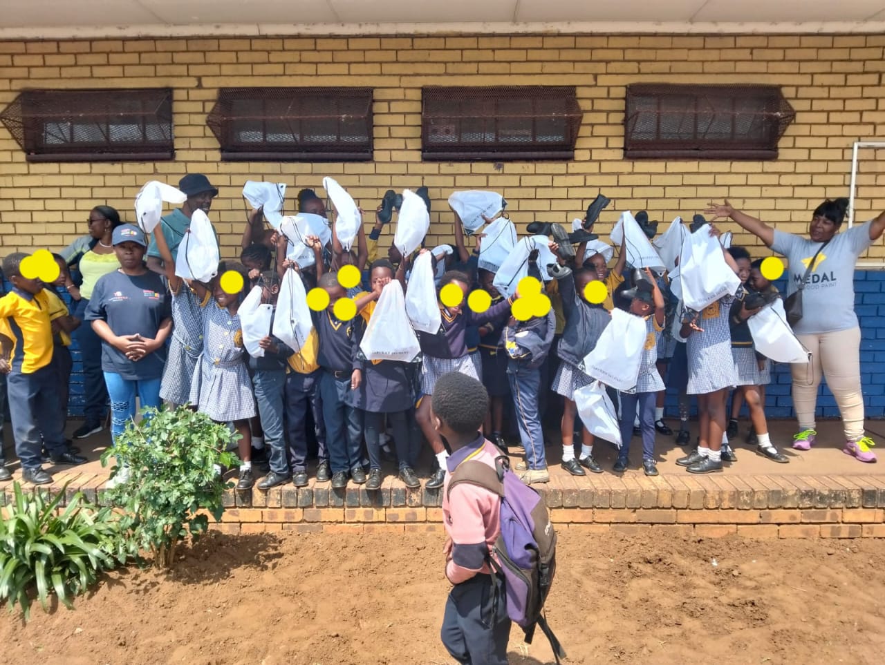 School children and staff celebrating a back-to-school donation of shoes and bags