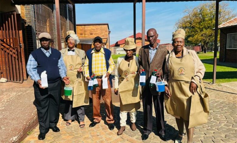 Senior citizens in Community Rise Uthando aprons holding detergent products they made at the Phiri skills graduation